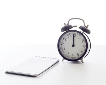 Close-up of clock on table against white background