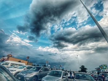 Vehicles on road against cloudy sky
