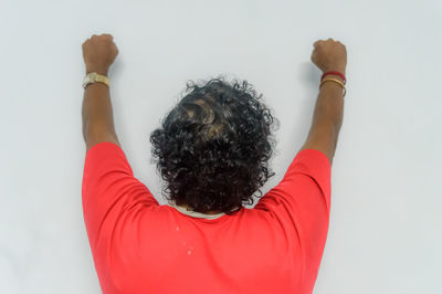 Rear view of woman with arms raised against white background