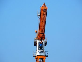 Low angle view of crane against clear blue sky