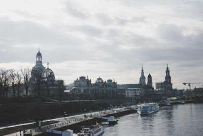 Boats in canal by buildings against sky in city