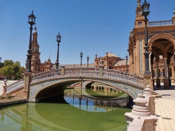 Arch bridge over river against sky in city