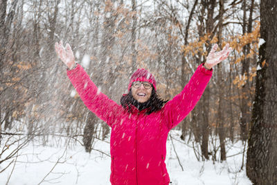 Portrait of young woman with arms outstretched in snow