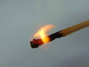 Close-up of burning candle against black background