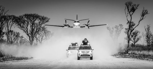 Airplane flying over road against sky