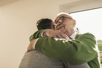 Smiling senior man hugging young man