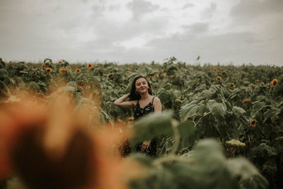 Young woman standing amidst sunflowers on field