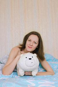 Portrait of smiling woman with stuffed toy on bed