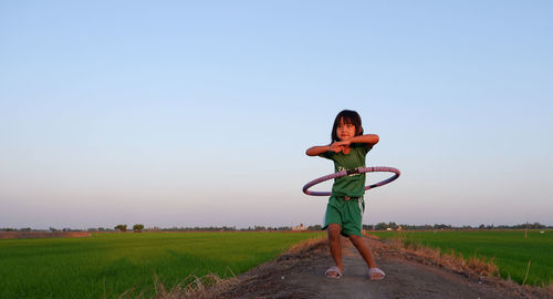 Full length of girl playing with plastic hoop amidst landscape