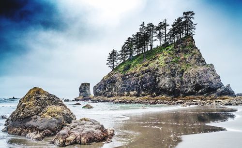 Rock formation on beach against sky