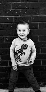 Portrait of cute boy smiling against brick wall