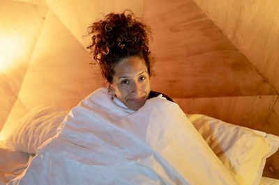 Portrait of young woman sitting on bed