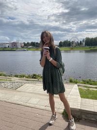 Woman drinking milkshake while standing outdoors