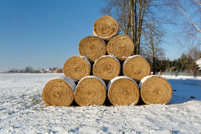 Stack of hay bales on field against clear sky