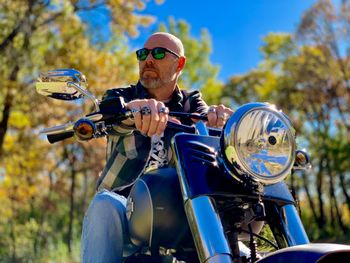 Low angle view of handsome bearded man sitting on motorcycle 