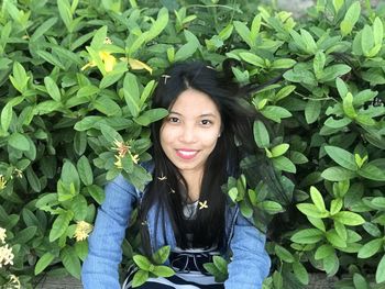 Portrait of smiling woman standing by leaves