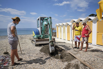 People working at shore against sky