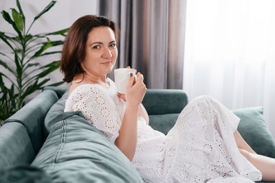 Woman drinking mug of coffee in cozy home atmosphere in the morning. real middle age plus size
