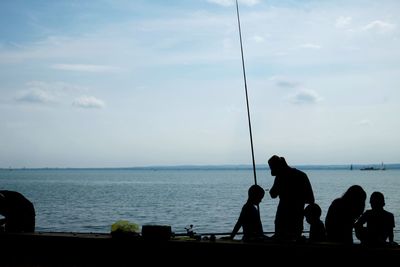 Man sitting by sea against sky