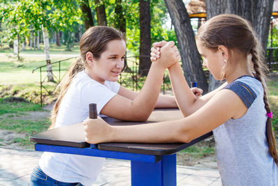 Friends playing arm wrestling on table in park