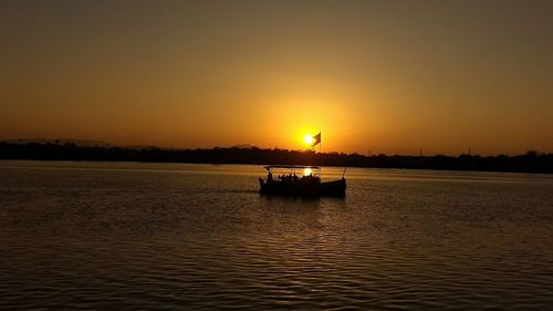 Silhouette boat in sea against sky during sunset