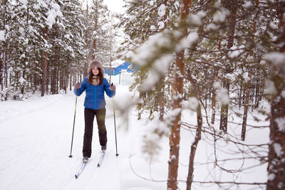 Woman skiing on snow against trees