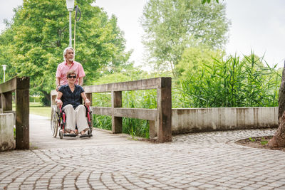 Full length of man sitting on seat against trees