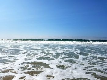 Scenic view of tide against blue sky