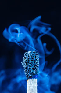 Close-up of burning candle against black background