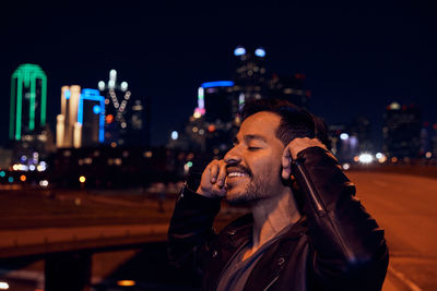 Portrait of young man using smart phone at night