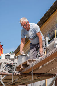 Masonry worker the bricklayer makes the facade of the house from gray bricks