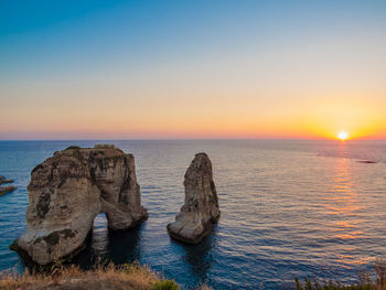 Rocks on sea against sky during sunset