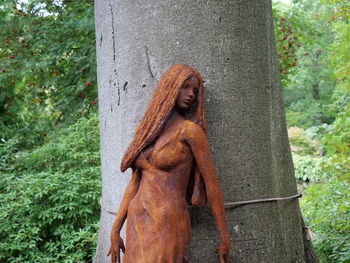 Statue against tree trunk in forest
