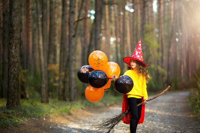 Full length of woman standing by tree in forest