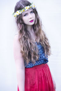 Portrait of young woman standing against white background