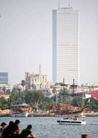 Boats in river by buildings against clear sky