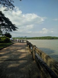 Footpath by railing against sky