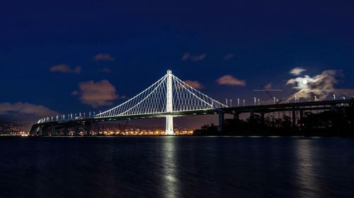 Illuminated san franciscooakland bay bridge over river at night