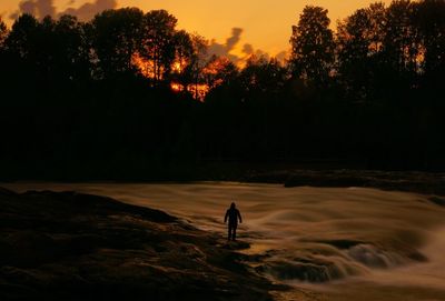 Silhouette person on field against sky during sunset