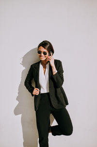 Full length of smiling young woman standing against white background