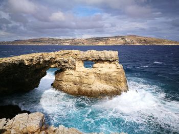 Rock formation on sea shore against sky