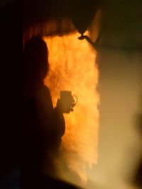 Silhouette person holding camera at night