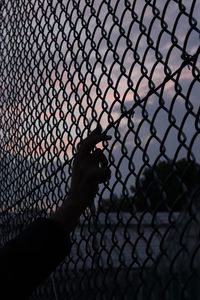Silhouette man seen through chainlink fence