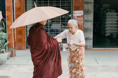 Woman holding umbrella standing on footpath in rain