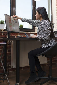 Side view of woman using mobile phone while sitting in gym