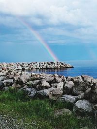 Scenic view of rainbow over sea against sky