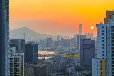 Buildings in city against romantic sky at sunset