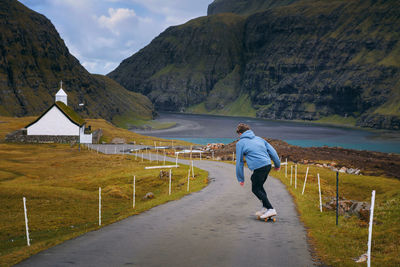 Rear view of man walking on road against mountains