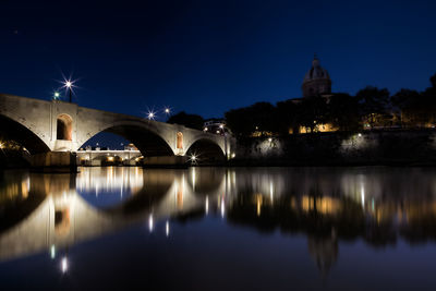 Illuminated bridge over river against sky at night