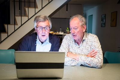 Portrait of senior man using laptop while sitting on sofa at home